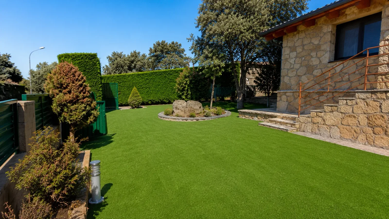 Jardín con césped artificial terminado junto a un chalet de piedra en Calpe